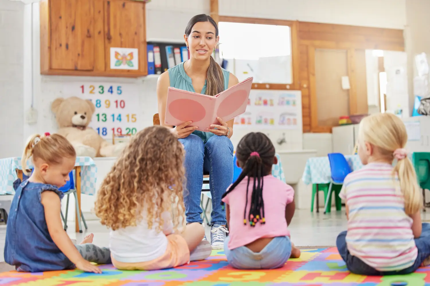 Everyone loves story time. Shot of a young woman reading to her preschool students.